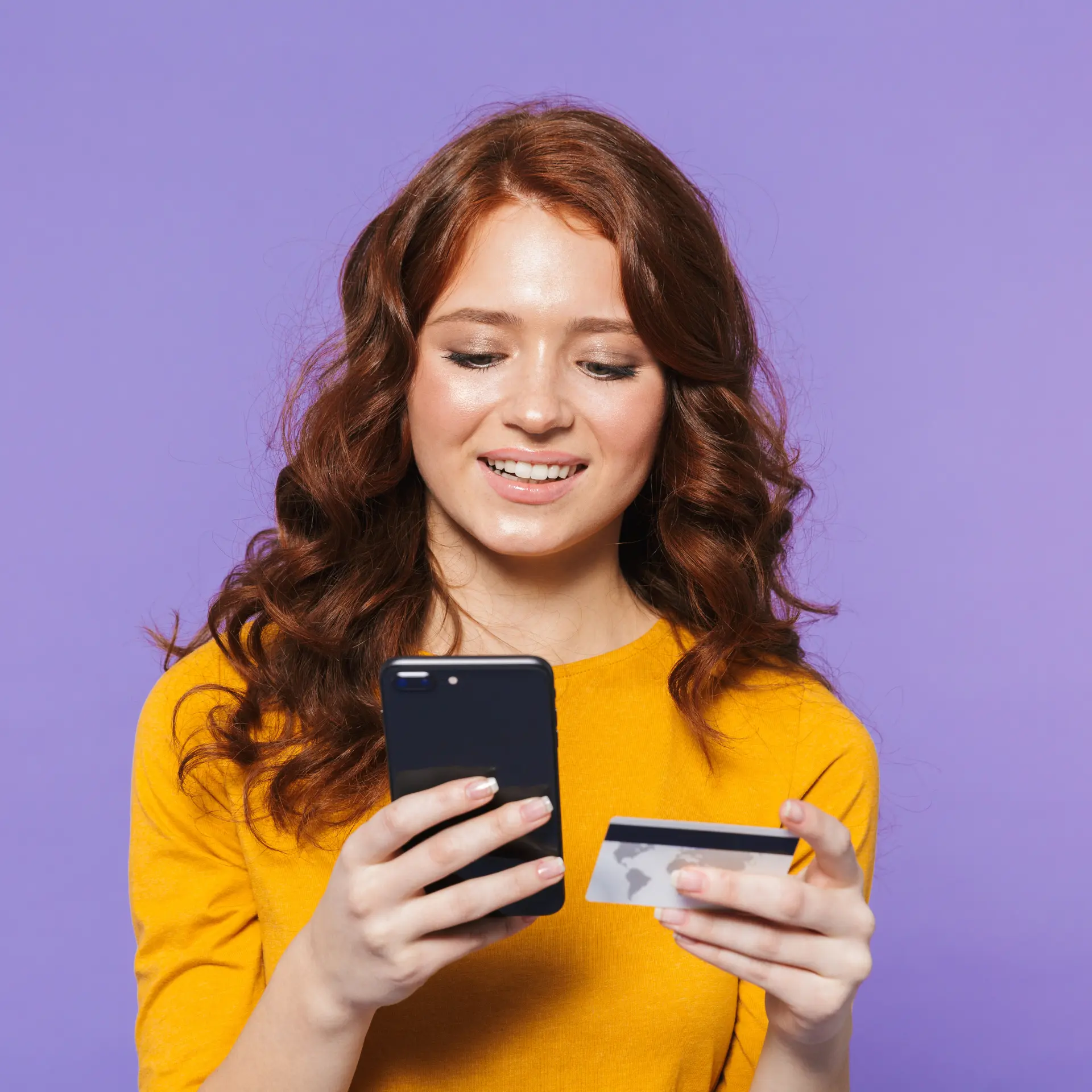 Момиче, държащо смартфона си и дебитната / кредитната си карта, пазарувайки с усмивка от онлайн магазин създаден от Studio ELSCAPE